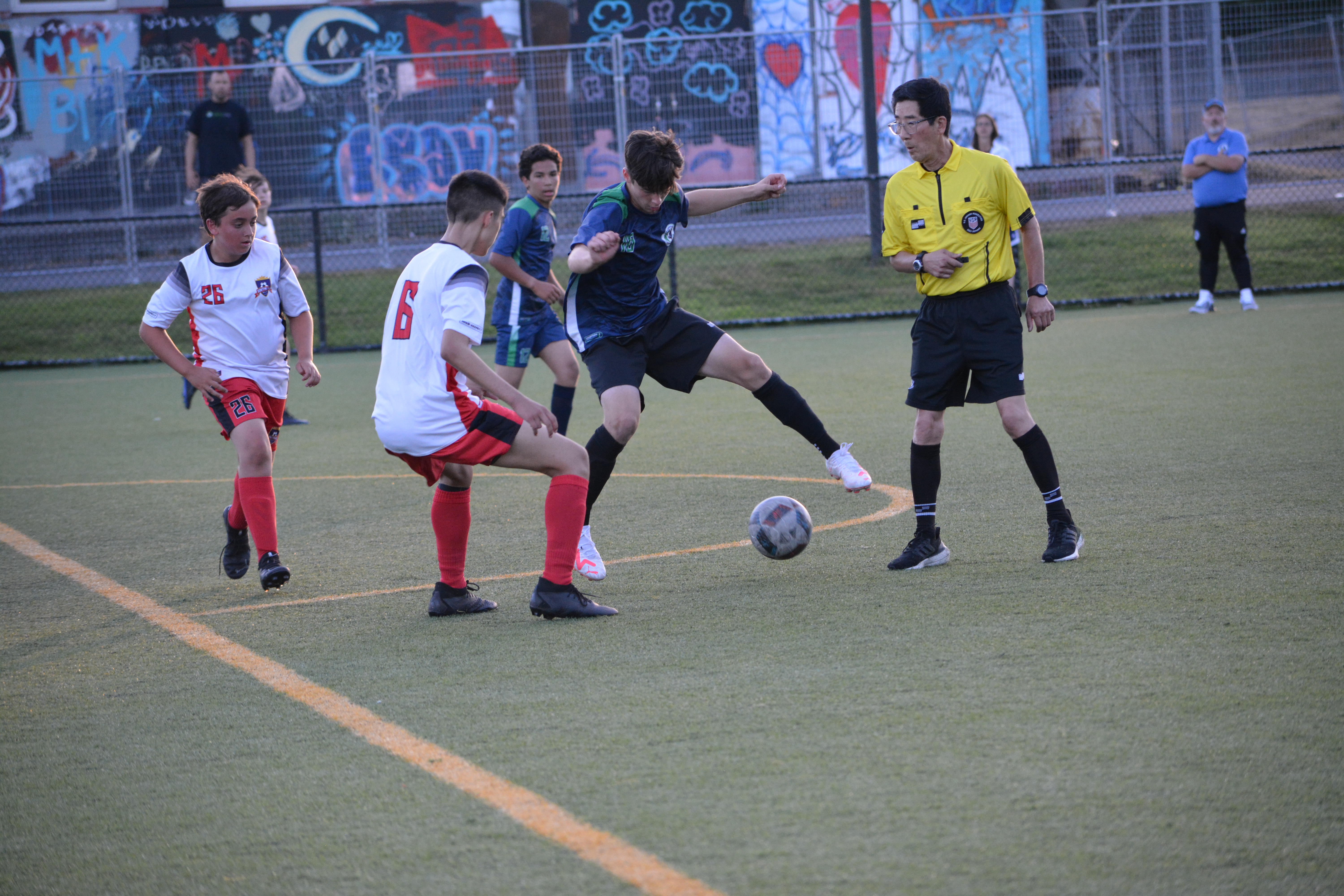 Soccer player controls the ball against a colorful background.