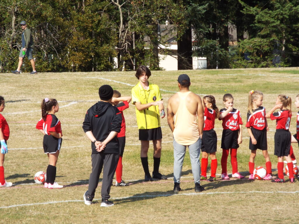 A group of soccer players listening to a referee.